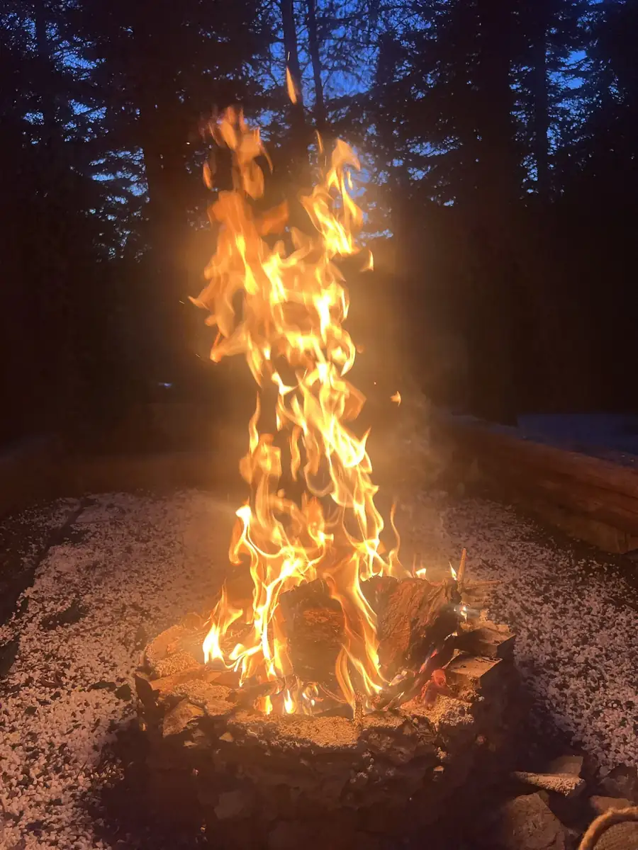 Tall flames in the stone fire pit at night