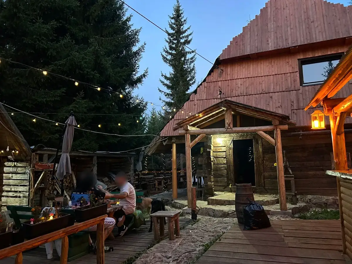 The log house at dusk, warm light and string lights